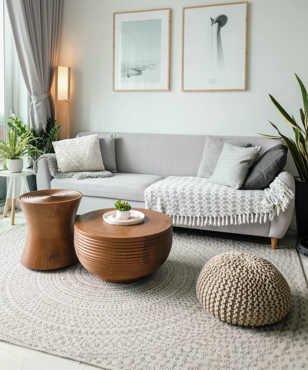 Bright, freshly cleaned living room with a light gray sofa, wood tables, and natural daylight